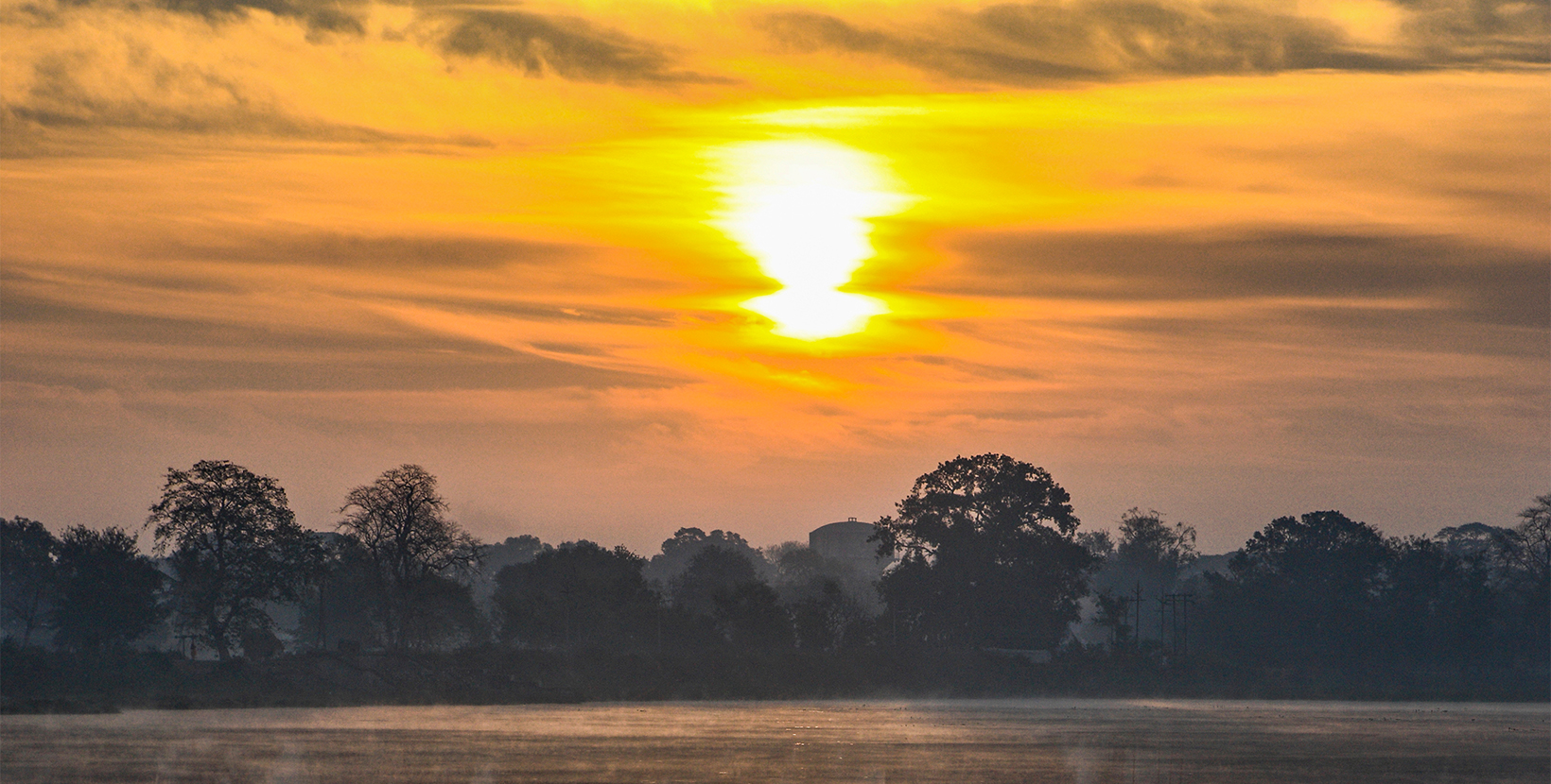 Golden  sky with clouds and morning  Sun reflected  in lake waters of  Dalpat Sagar  at Jagdalpur, Bastar, Chhattisgarh, India., Asia