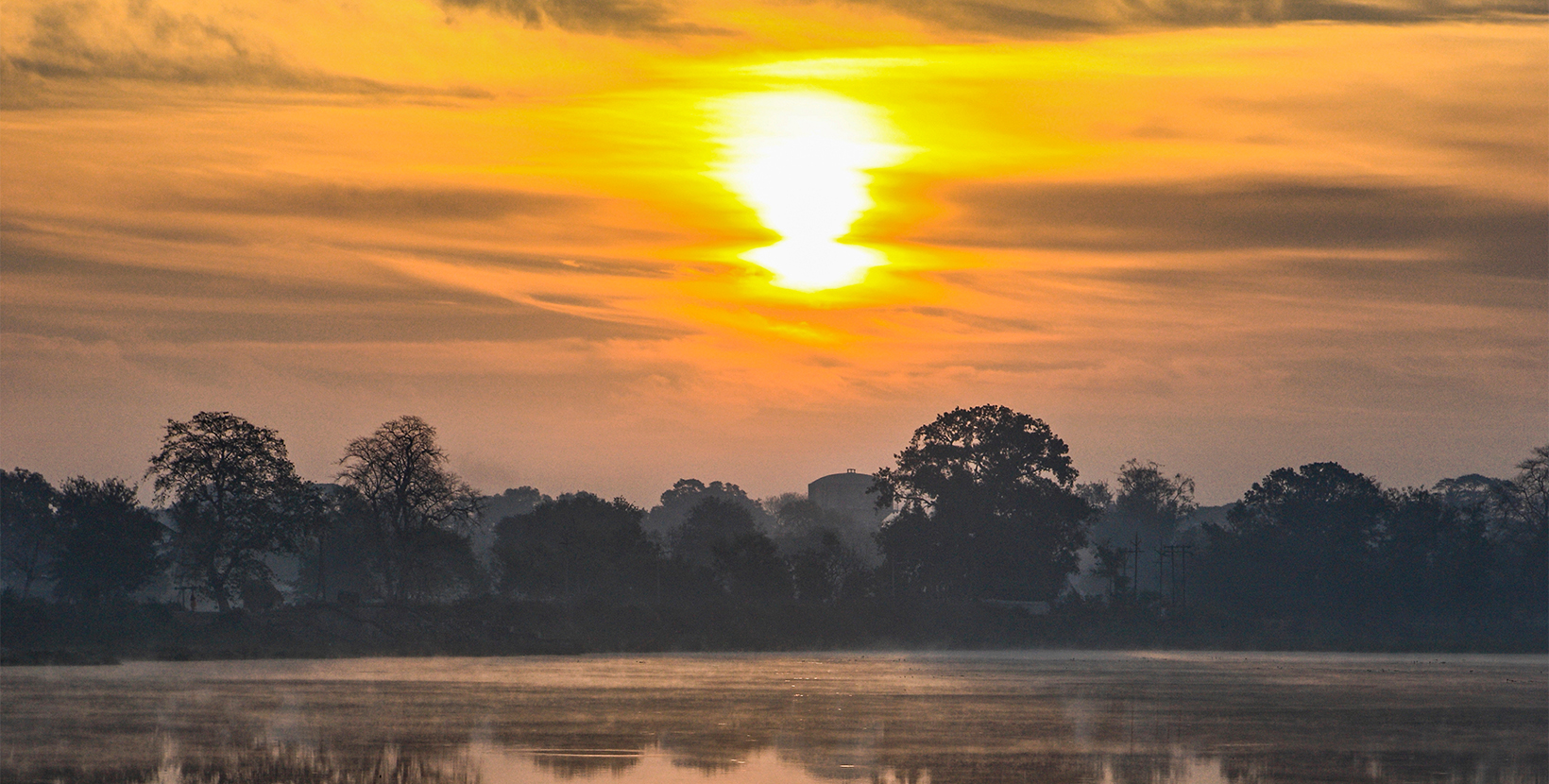 Golden  sky with clouds and morning  Sun reflected  in lake waters of  Dalpat Sagar  at Jagdalpur, Bastar, Chhattisgarh, India., Asia