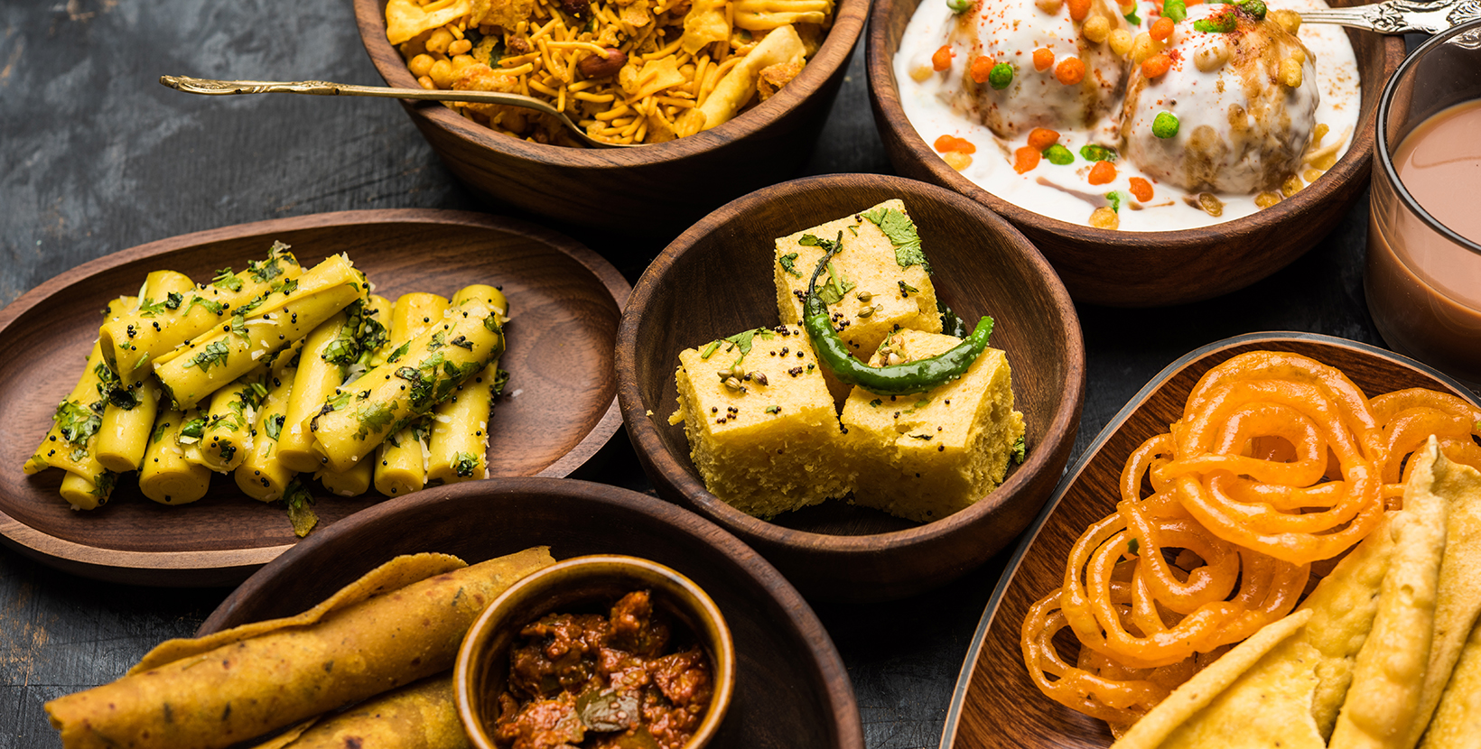 Group of Gujarati snacks like jalebi-fafda, thepla, khaman dhokla, aloo bhujiya, khandvi,khakra, dahi vada, gathiya with hot tea