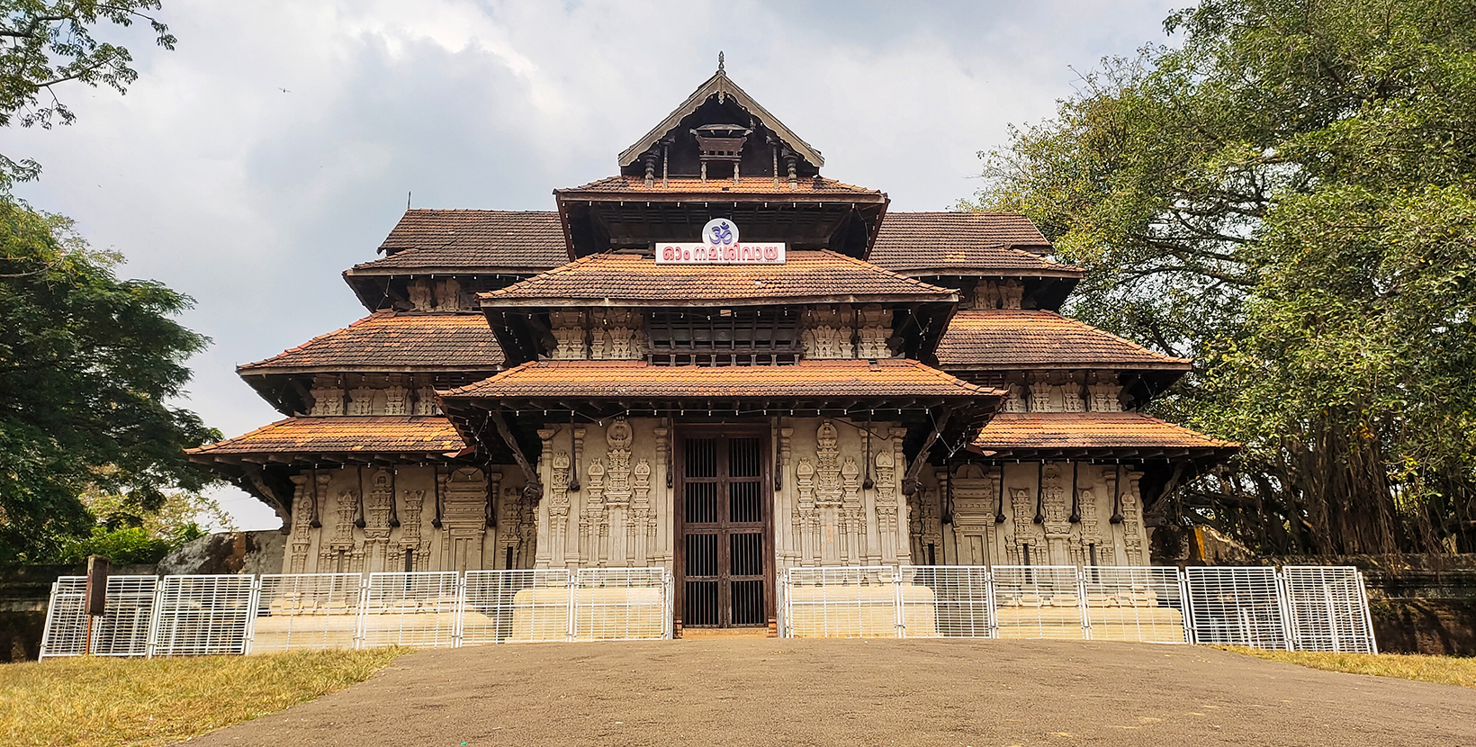 Vadakkumnathan or lord shiva ancient old traditional style south indian hindu religion stone temple building in kerala, thrissur. Front view with Om Namah Shivaya Mantra text in Malayalam language.