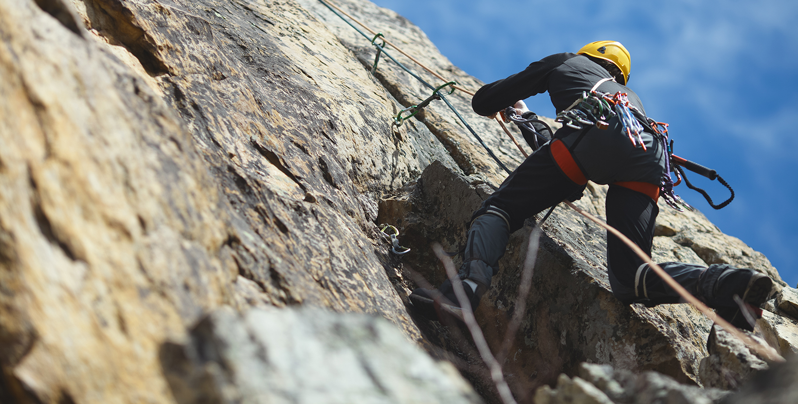 Climber climbs on the rock wall against a blue sky. Climbing gear. Climbing equipment.