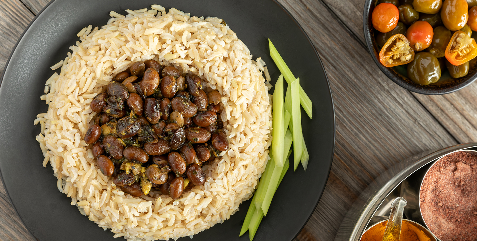 Black soybeans cooked in spices served with brown basmati rice and celery stalks. Bhat ki Chudkani - a traditional dish of the Kumaon region. Pickled chilies and a box with spices on the side.