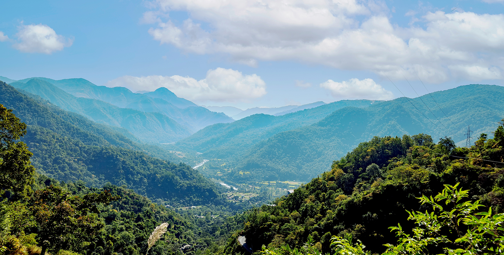 Scenic view of a green valley surrounded by lush mountains under a cloudy sky in Nagari Gaon, Bhowali, Bhimtal Road Sukha Uttarakhand India